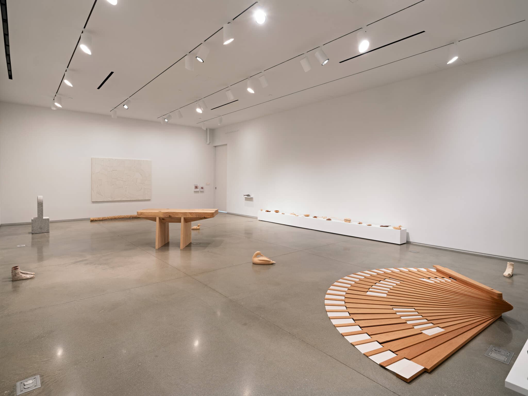 Sculptures are placed on the floor throughout a gallery space.